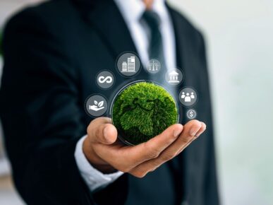 torso of man in a business suit with his hand outstretched holding a small ball that looks like the earth